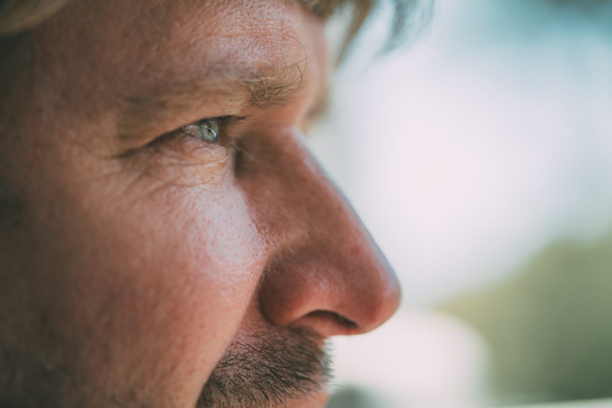 Plan rapproche sur le profil de l'ambassadeur Tom Frager se concentrant sur quelque chose hors cadre. On peut voir en detail ses yeux le pont de son nez et une partie de ses cheveux.